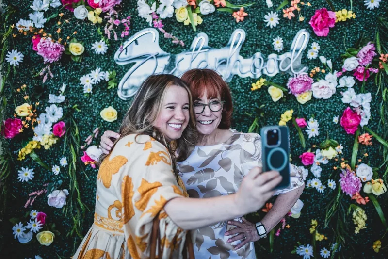 Two women embracing at the Sisterhood photo booth