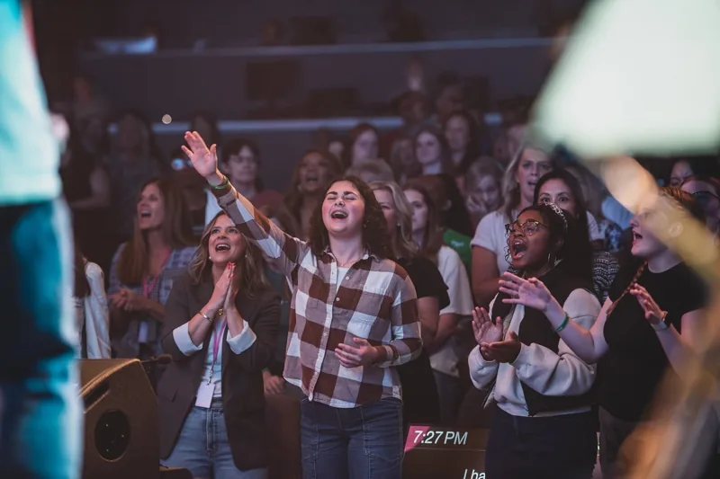Women singing and lifting their hands during worship