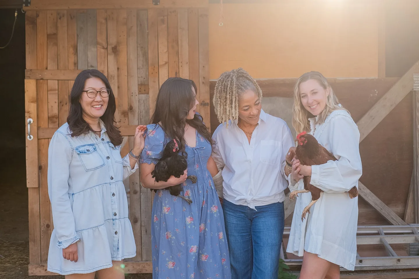 Four women laughing together outside a barn in the 2027 photoshoot