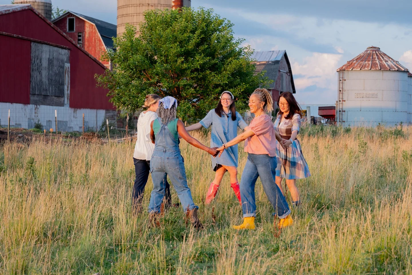 Women holding hands in a circle in a field for the 2027 Lead Me photoshoot