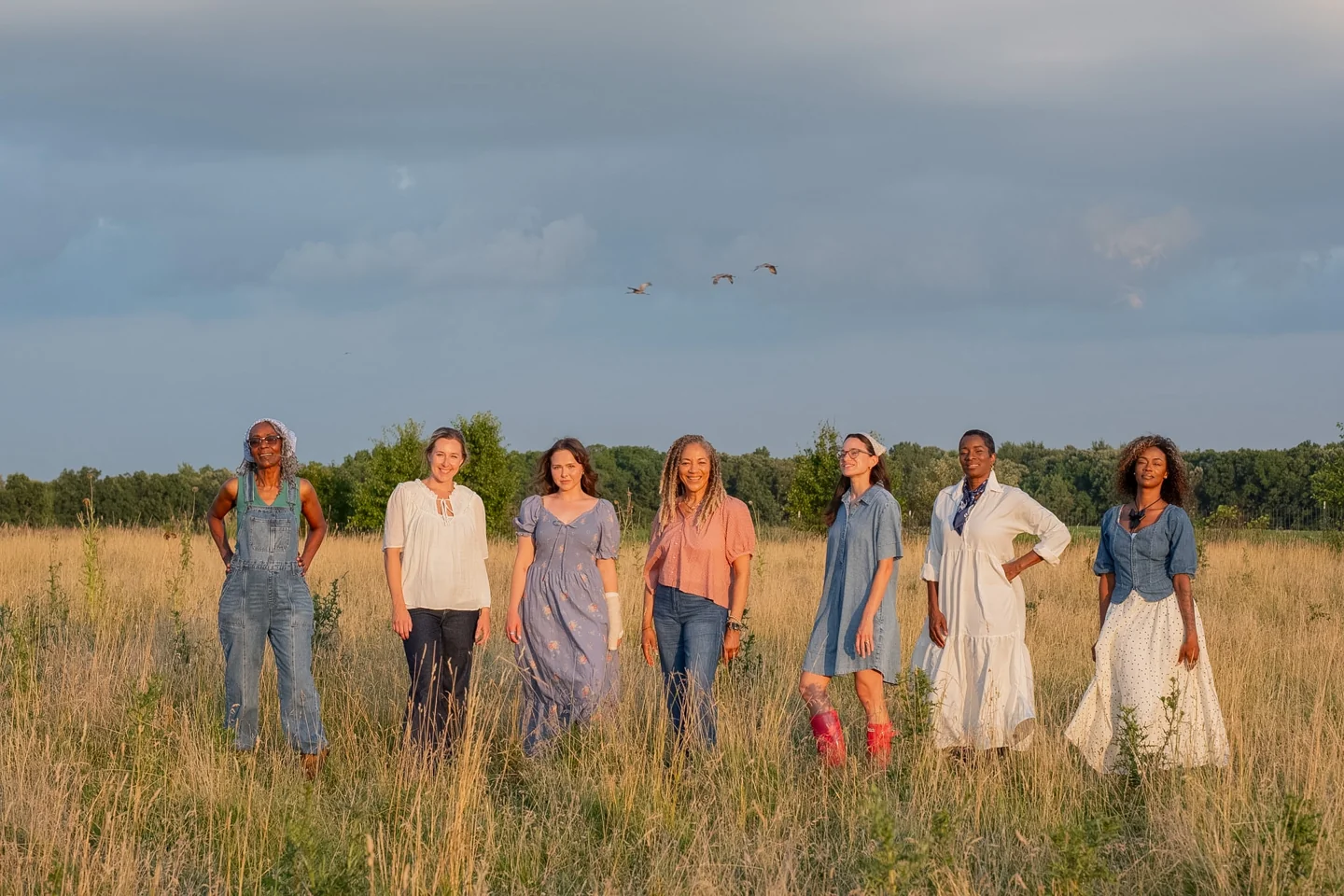 Seven women gathered together in a sunlit field for the 2027 photoshoot